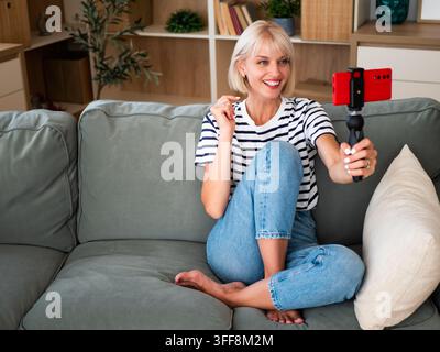 Woman creating engaging social media content from the comfort of her modern living room. Stock Photo