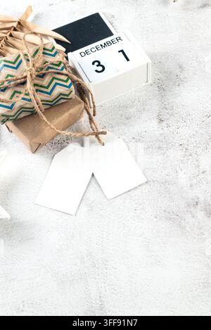 White blank paper tag on craft gifts boxes and Christmas decor on grey conkrete background. Christmas greeting card mockup. Stock Photo