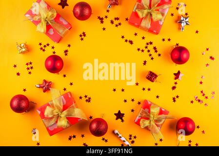 Christmas and New Year compositions with gifts boxes wrapped in red paper with golden ribbon bow on yellow background with empty circle for your greet Stock Photo