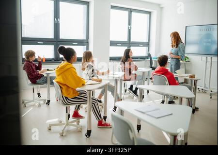 Diverse teenage students attending marketing class in modern classroom. Stock Photo