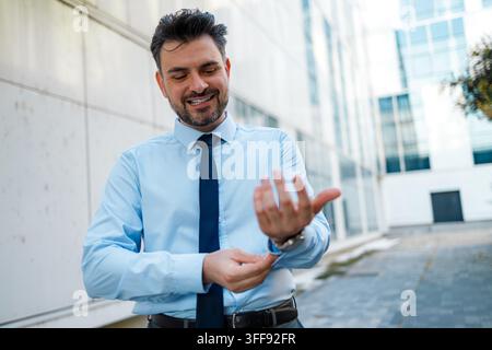 A man is in an office area adjusting his shirt sleeves. He looks happy and relaxed. Stock Photo