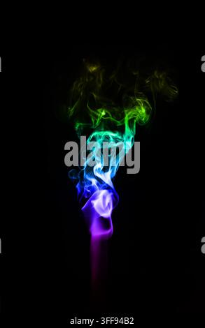 A delicate wisp of multicoloured smoke curling gracefully against a deep black background, creating an ethereal and minimalist atmosphere Stock Photo