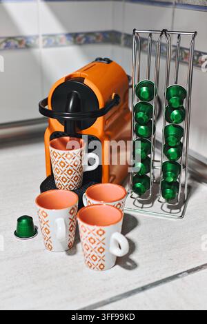 Closeup of espresso machine, coffee mugs and aluminum capsules on kitchen counter Stock Photo