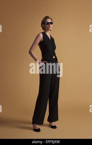 A young woman in a chic black mini dress strikes a dynamic pose in a professional Istanbul studio. Stock Photo