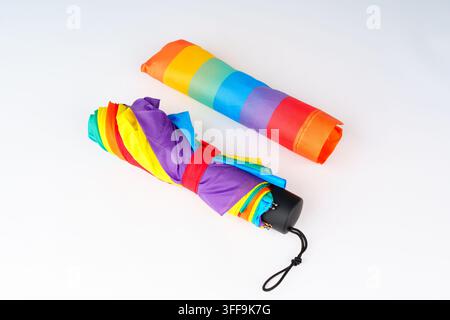 Step-by-step sequence showing four stages of opening a compact, colorful folding rainbow umbrella, starting from closed in its pouch to fully open on Stock Photo