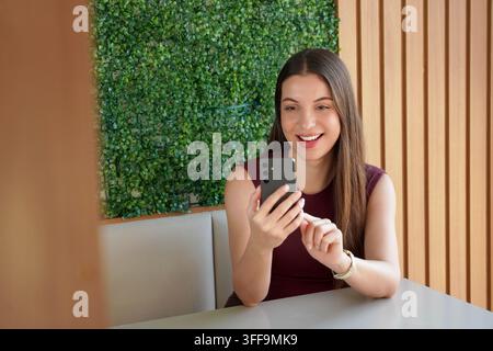 Smiling Brazilian business woman using banking app on mobile phone indoor Stock Photo