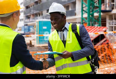 Engineers shaking hands on construction site Stock Photo