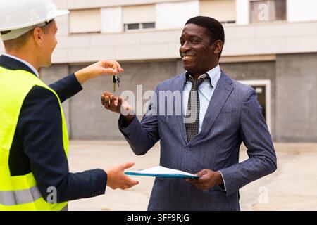 Architect transmits keys to the new african american businessman shopping center Stock Photo