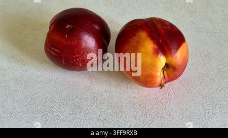 Two ripe fresh nectarines arranged on a clean white surface with generous copy space, representing summer fruit and healthy eating. Stock Photo