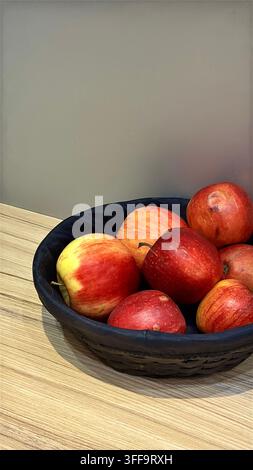 Minimalist arrangement of fresh red apples in a dark bowl on a light surface, with generous copy space for food and seasonal concepts. Stock Photo