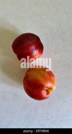 Two ripe nectarines arranged on a clean white surface with generous copy space, creating a minimalist summer fruit composition. Stock Photo