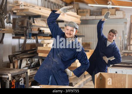 Two funny sawmill workers perform various funny moves Stock Photo