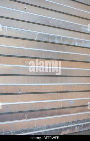 Abstract perspective view of a clean ribbed steel wall panel featuring linear silver horizontal lines and natural light reflections. Stock Photo