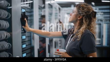 System Technician Cleans Server Rack Glass Doors while Teammate Uses Vacuum Hose to Clear Equipment Dust. Systematic Hardware Cleaning and Facility Management Safeguard Enterprise Network Operations. Stock Photo