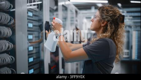 System Technician Cleans Server Rack Glass Doors while Teammate Uses Vacuum Hose to Clear Equipment Dust. Systematic Hardware Cleaning and Facility Management Safeguard Enterprise Network Operations. Stock Photo