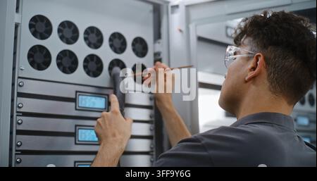 Technician Extracting Dust Particles From Active Server Cooling Grates Using Brush and Vacuum Tube. Specialized Physical Servicing Preserves Internal Hardware Components in Enterprise Data Centers. Stock Photo