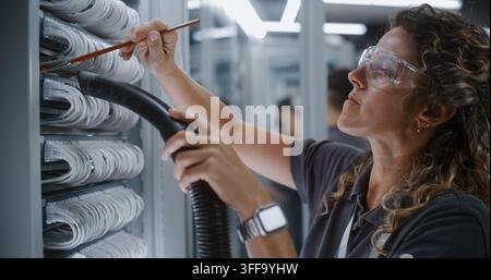 Engineer Delicately Cleans Network Cables Using Brush and Vacuum Hose. Active Role of Women in STEM Within Data Center Maintenance Ensures Reliable and Continuous Operation of Modern Cloud Systems. Stock Photo