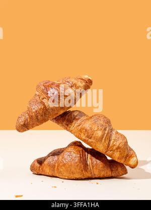 Stack of fresh croissants on yellow and orange background. Creative trendy layout and concept of healthy food or french breakfast. Copy space. Stock Photo