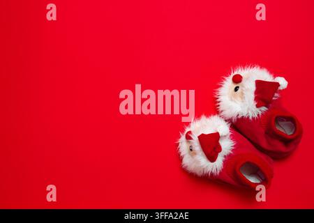 New year, Christmas slippers in form of santa claus with white soft fur on red background with place for text. Funny, cozy, fluffy children shoes Stock Photo