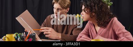 Young man and woman collaborate on a project, sharing ideas and strategies while working diligently. Stock Photo