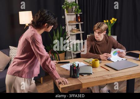 Two young coworkers are working together in a stylish office, deeply engaged in discussion. Stock Photo