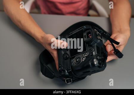 Close-up top view of photographer assembling black digital camera with external battery grip for extended use, preparing for photography, shooting, an Stock Photo