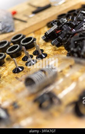 Closeup of bicycle parts like bolts bearings and black metal components on wooden workbench in repair workshop Stock Photo