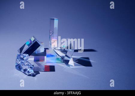 Glass prisms refracting light creating spectrum on blue background Stock Photo