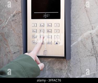 Hand pressing button on metallic keypad access system mounted on marble wall, concept of security and access control Stock Photo