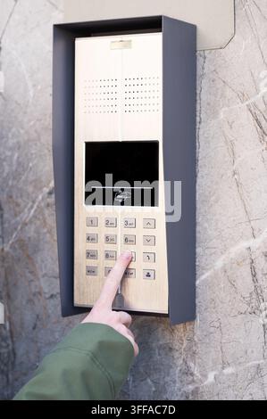 Hand pressing button on metallic keypad access system mounted on marble wall, concept of security and access control Stock Photo