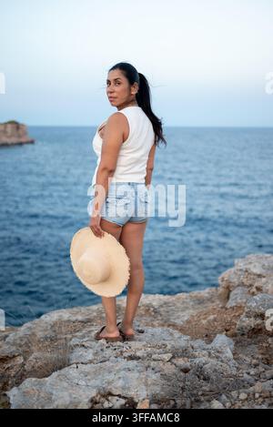 Latina Woman Standing on Rocky Cliff Looking at Camera Stock Photo
