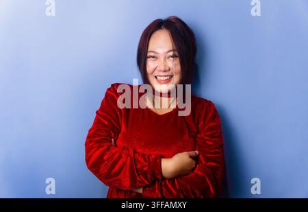 Happy Asian Woman in Red Velvet Dress with Arms Crossed Stock Photo