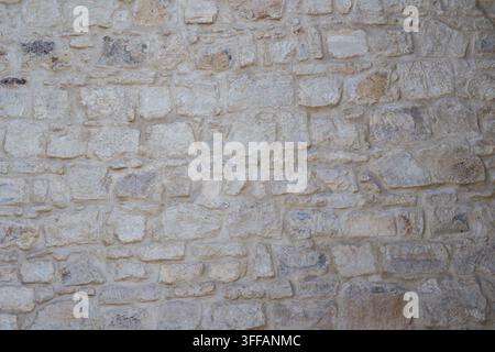 Pale stone masonry wall with irregular blocks forming a rustic background Stock Photo