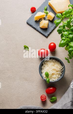 Parmesan cheese; cherry tomatoes and fresh basil on a slate board on a light background. Italian cuisine and antipasto concept. Top view; copy space. Stock Photo