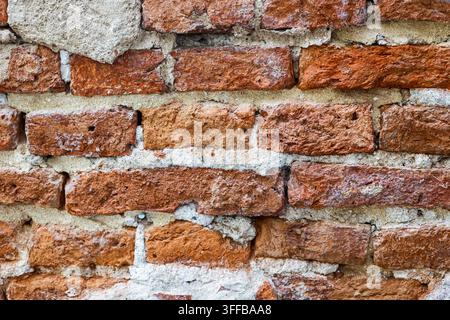 Close up of an old weathered red brick wall with thick grey cement mortar, showing rough rustic decay for architectural backgrounds. Stock Photo