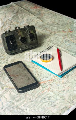 Wilderness planning with map, compass, smartphone, trail camera Stock Photo