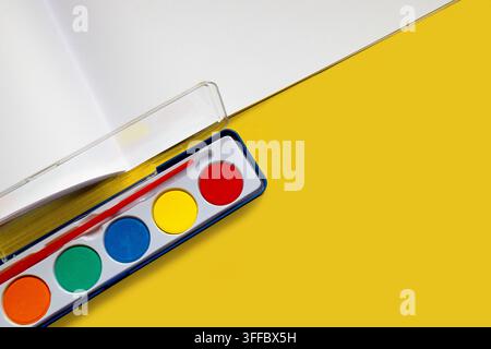 Colorful Watercolor Paint Palette and Brush on Bright Yellow Background Stock Photo