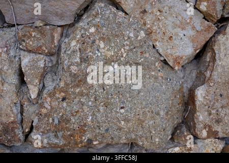 Detailed close up of rough natural stone wall texture showing rustic patterns in Barcelona Spain outdoor setting Stock Photo