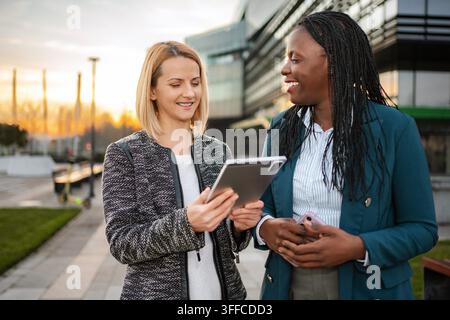 Businesswomen collaborating outdoors using digital tablet technology Stock Photo