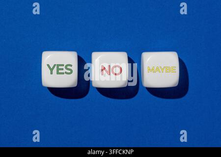 Three white dice displaying the words YES, NO, and MAYBE on a blue background. Decision making, choices, survey options, uncertainty concept. Stock Photo