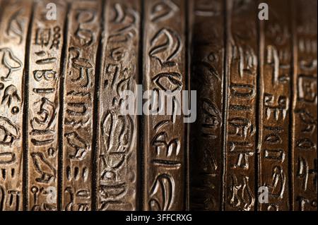 macro close-up of bronze-toned metal bands embossed with Egyptian-style hieroglyphic symbols, showing texture, patina and decorative detail Stock Photo
