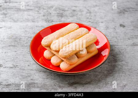 Stacked Savoiardi ladyfinger biscuits served on bright red plate Stock Photo