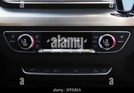 Close up view of sleek car dashboard. Illuminated digital display shows automatic 3-zone climate control, set to "LO AUTO" for driver and passenger, a Stock Photo