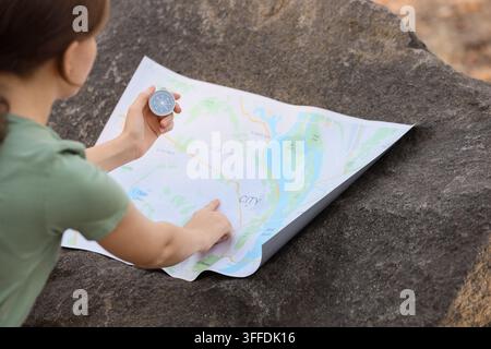 Travel planning and navigation, woman using a compass and paper map to find direction while hiking in nature for adventure and exploration Stock Photo