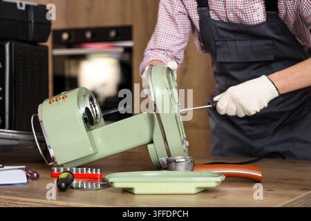 Male technician repairing coffee machine in kitchen, closeup Stock Photo