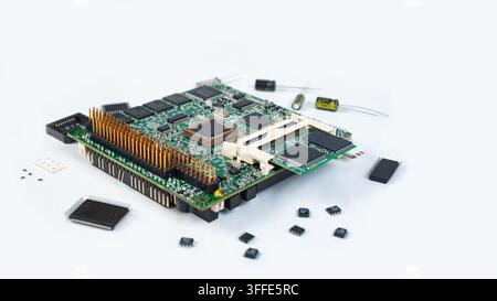 A circuit board lies on a white surface surrounded by various electronic chips. Tools are nearby for assembly or repair work. Stock Photo