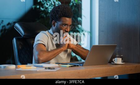 Burnout exhausted African American business man thinking about difficult laptop trouble at late night office tired businessman male guy worker Stock Photo