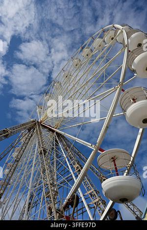 Close-up view from below of white Ferris wheel structure and passenger gondolas Stock Photo