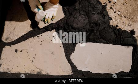 Minimalist background with stark textures. Harsh direct light creates deep black shadows on rough stone and gritty grout. Natural, raw, and modern des Stock Photo