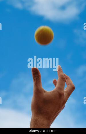 Close up of Man Hand Throwing Tennis Ball into Air Stock Photo